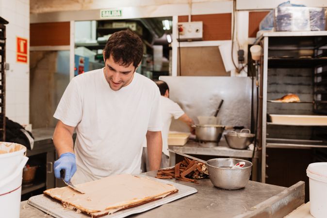 Male confectioner preparing cake in kitchen