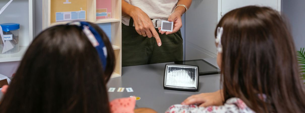 Unrecognizable teacher explaining to her students the parts of a sustainable house showing a solar panel