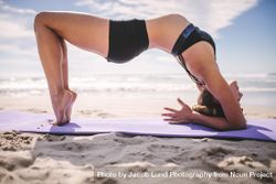 Female doing stretching workout on a yoga mat at the beach 4mP3z5