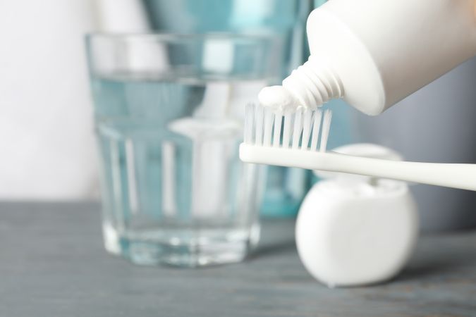 Toothbrush with toothpaste on background with dental care tools, close up