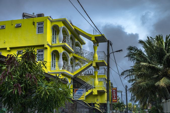 Bright yellow buildings with palm trees against cloudy sky