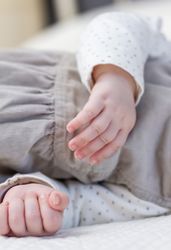 Hands closeup of baby girl sleeping over bedcover