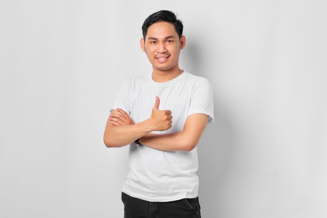 Asian male in grey studio making thumbs up