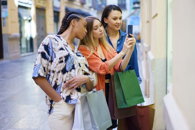 Curious women on shopping trip taking picture of storefront