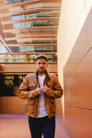 Confident guy walking near modern wall