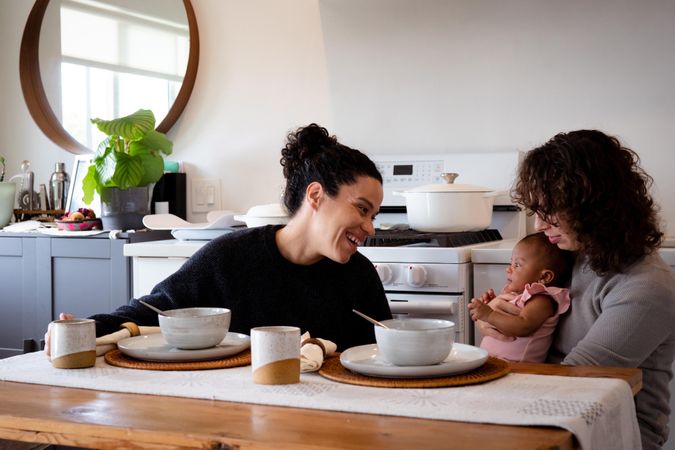 Two women eating soup with baby daughter at their dining table