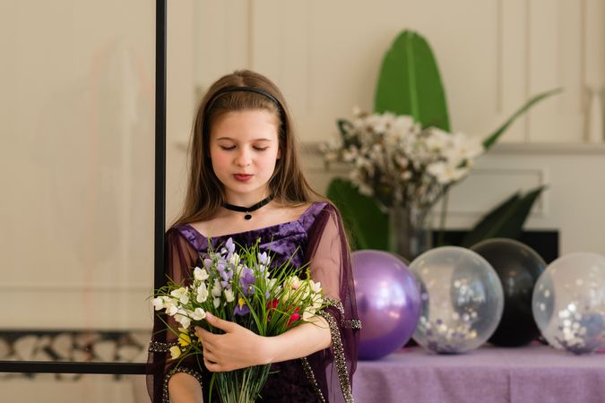 Girl looking at bouquet of flowers at birthday party.