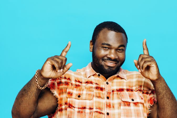 Portrait of a smiling man pointing up, isolated on blue background