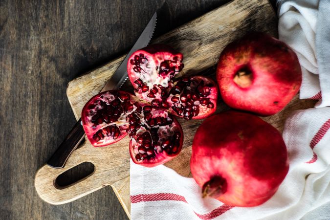 Fresh cut pomegranate on breadboard with kitchen towel