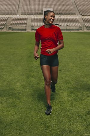 Smiling female soccer playing running on the field