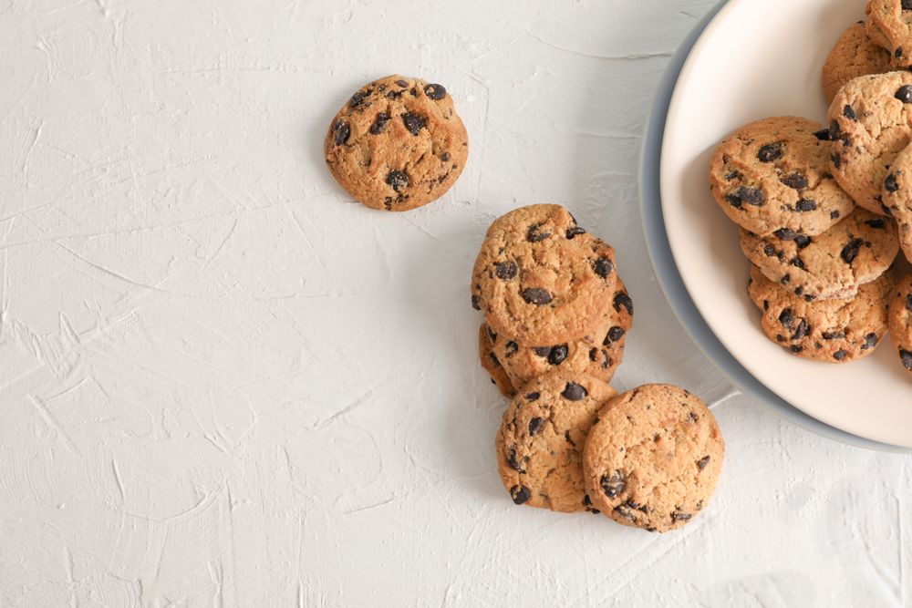 Plate with tasty chocolate chip cookies  on gray background, top view. Space for text