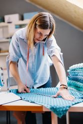 Concentrated seamstress talking on smartphone