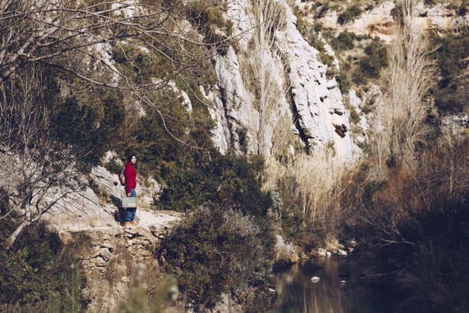 Traveling woman on lake in rocky cliffs
