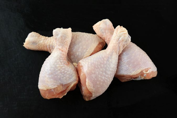 Raw chicken legs on dark background