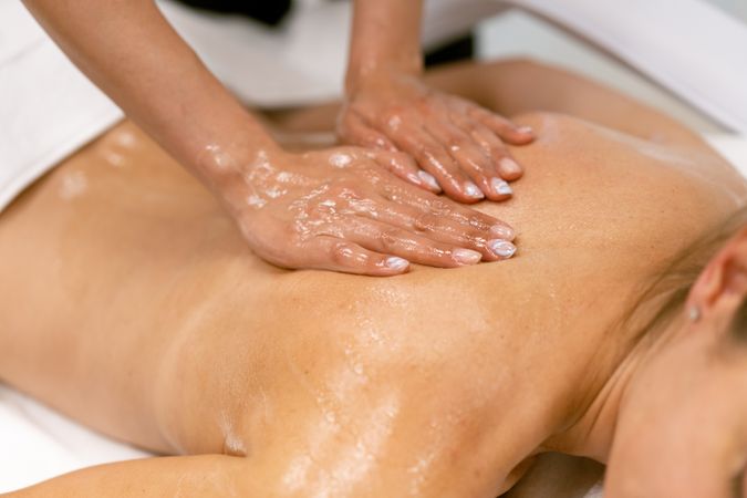 Masseuse giving a massage to a person’s back with oil