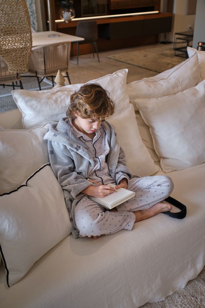 Boy studying and writing information in paper notebook at home