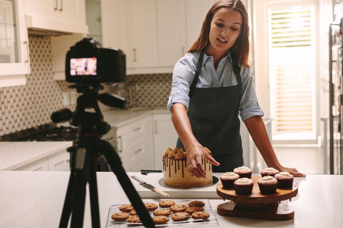 Young woman recording video lesson with pastries on counter