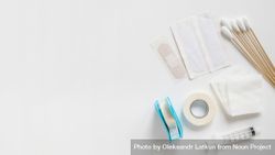 Bandages, cotton swabs, sterile gauze, medical tape, and syringe on bright background 49gaW0