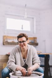 Woman potter shaping vessel on wheel