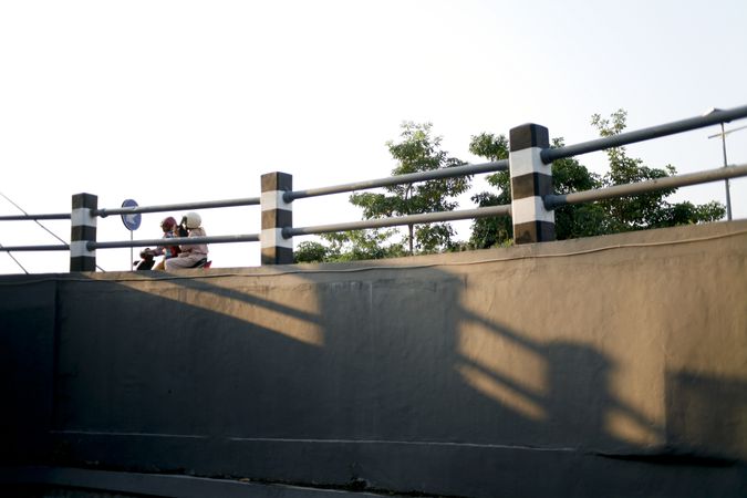 Rail on bridge with a couple on a motorcycle