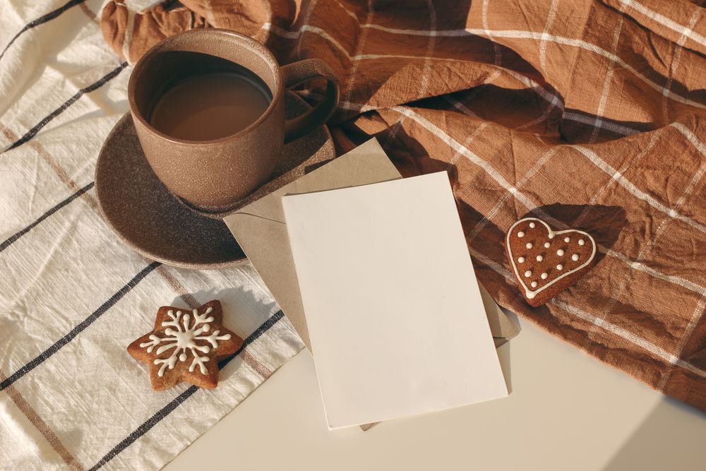 Cup of coffee, star and heart shaped gingerbread cookies on sunny checkered table cloth