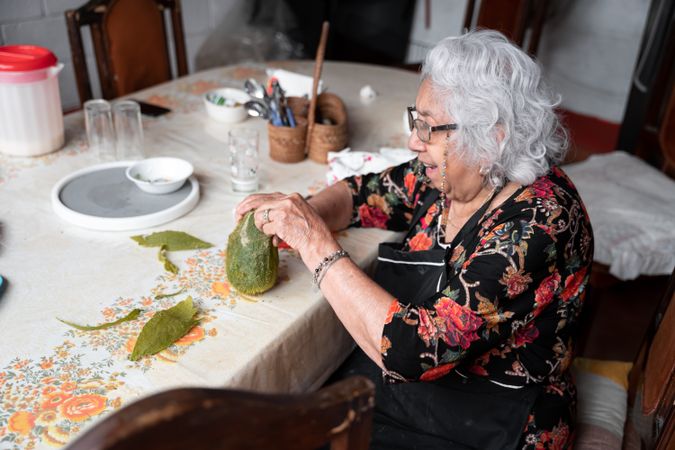 A Mexican woman is peeling a fresh cooked chayote for a snack on a table