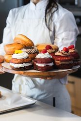 Crop woman with Berliners on tray in bakery