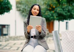 A stylish woman used her tablet surrounded by shopping bags in a vibrant urban setting