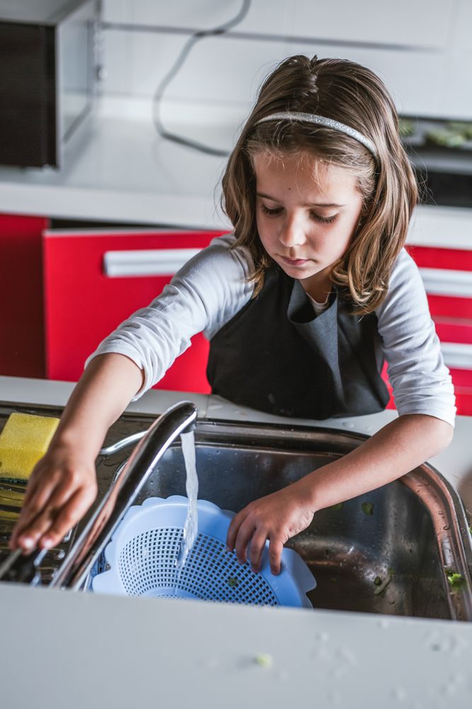 Girl washing dishes in kitchen