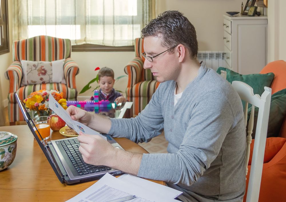 Father working in home office and son playing