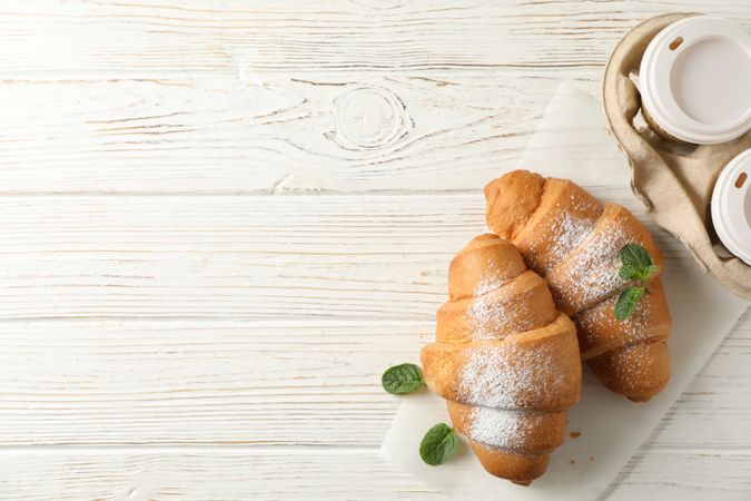 Croissant on wooden table with to go coffee, with space for text