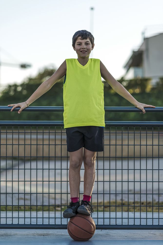Portrait of a young teen wearing a yellow basketball sleeveless smiling