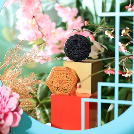 Two Chinese mooncakes surrounded by vibrant flowers