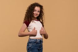 Young girl showing thumbs-up pose, smiling confidently