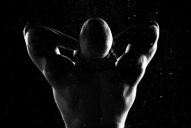 Anonymous muscular male under rain