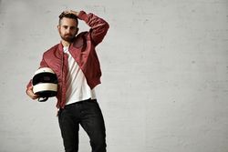 Man in burgundy leather jacket holding biker helmet