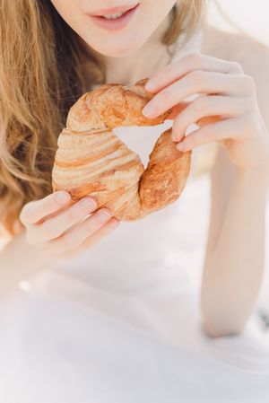 Cropped image of blonde woman hold croissant