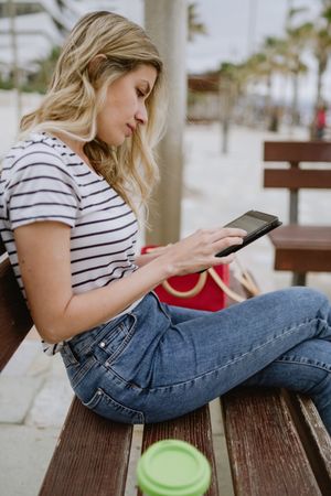Woman sitting on bench and using tablet