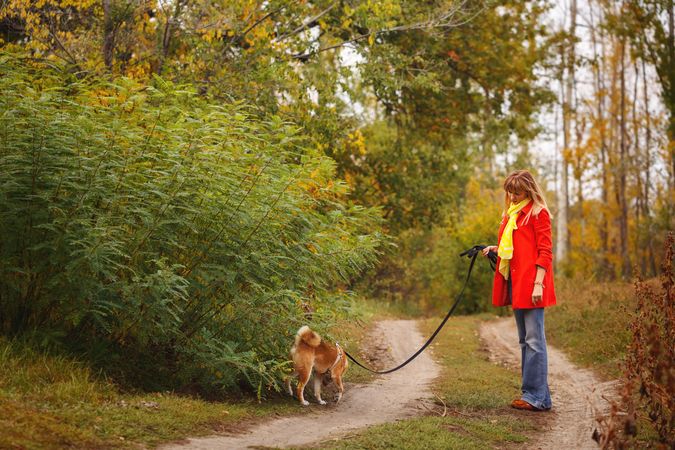 Female in red coat walking with dog in park