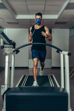 Male runner wearing mask on treadmill in sports science laboratory testing biomechanics