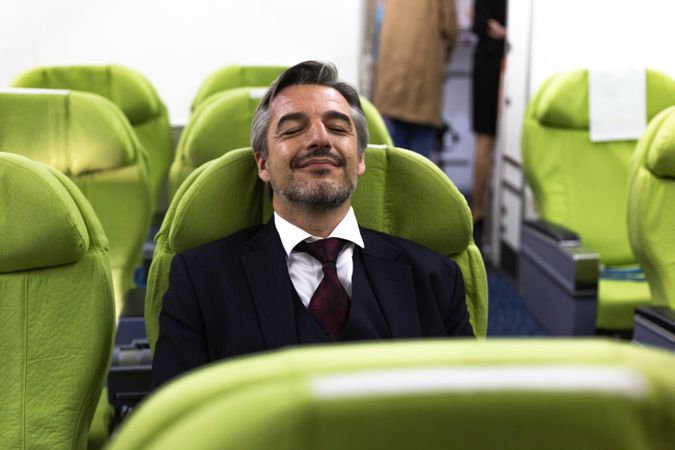 Content man with eyes closed in empty airplane cabin