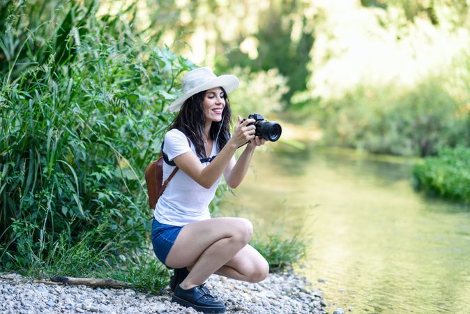 Woman sitting with SLR camera near river