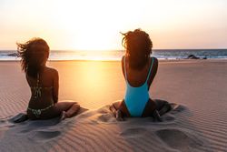 Content Black woman on tropical beach at sunset