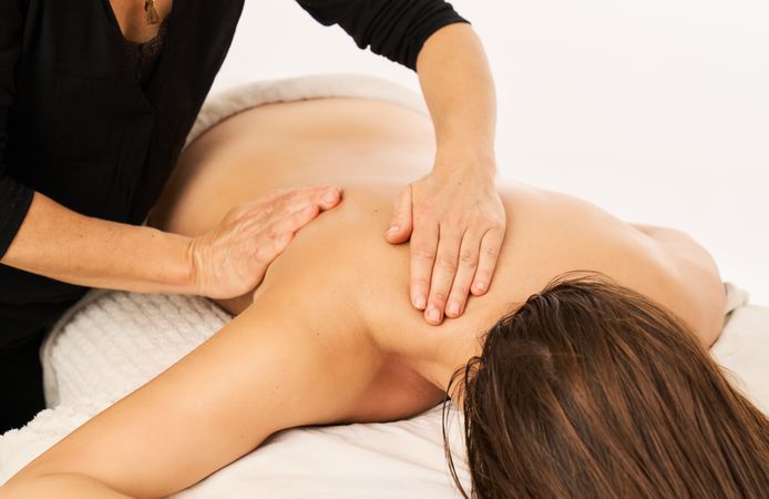A masseuse massaging the shoulder of a woman with a shoulder