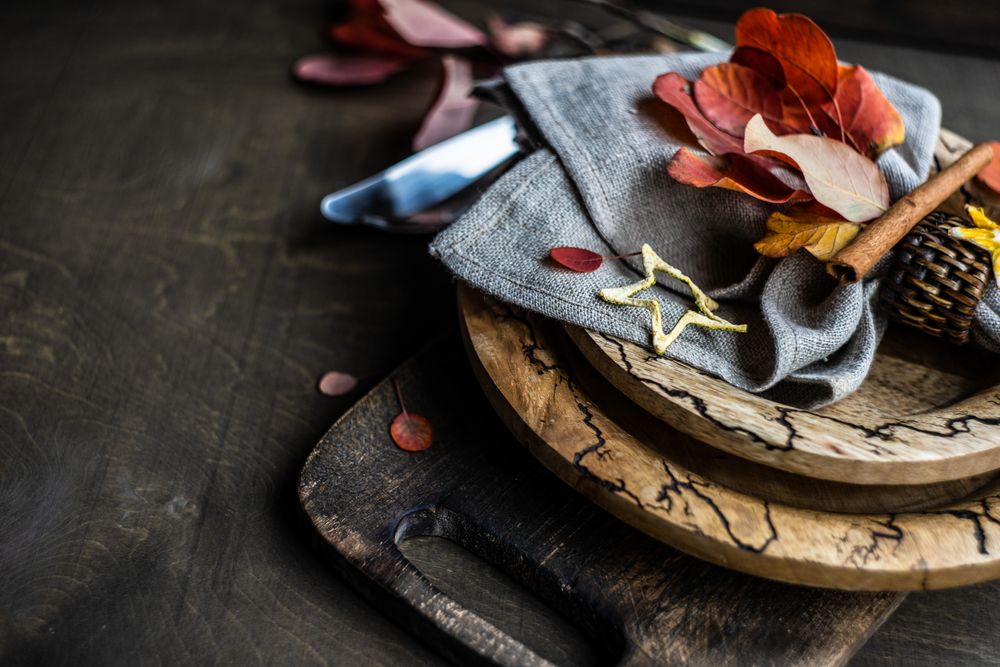 Fall place setting with yellow and red leaves on rustic background with copy space