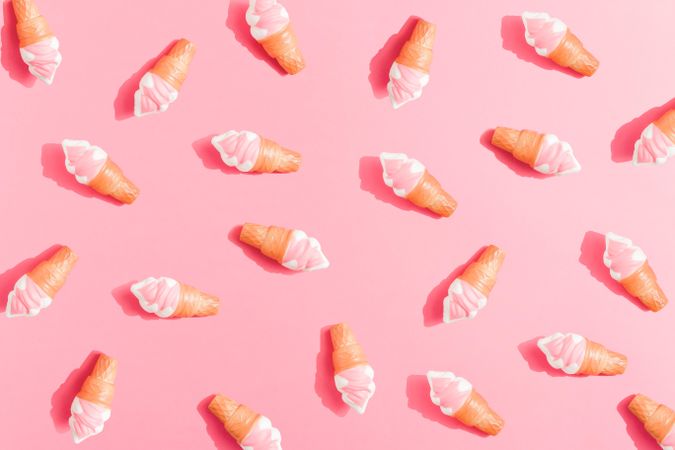 Scattered pink ice cream in cones on pink background