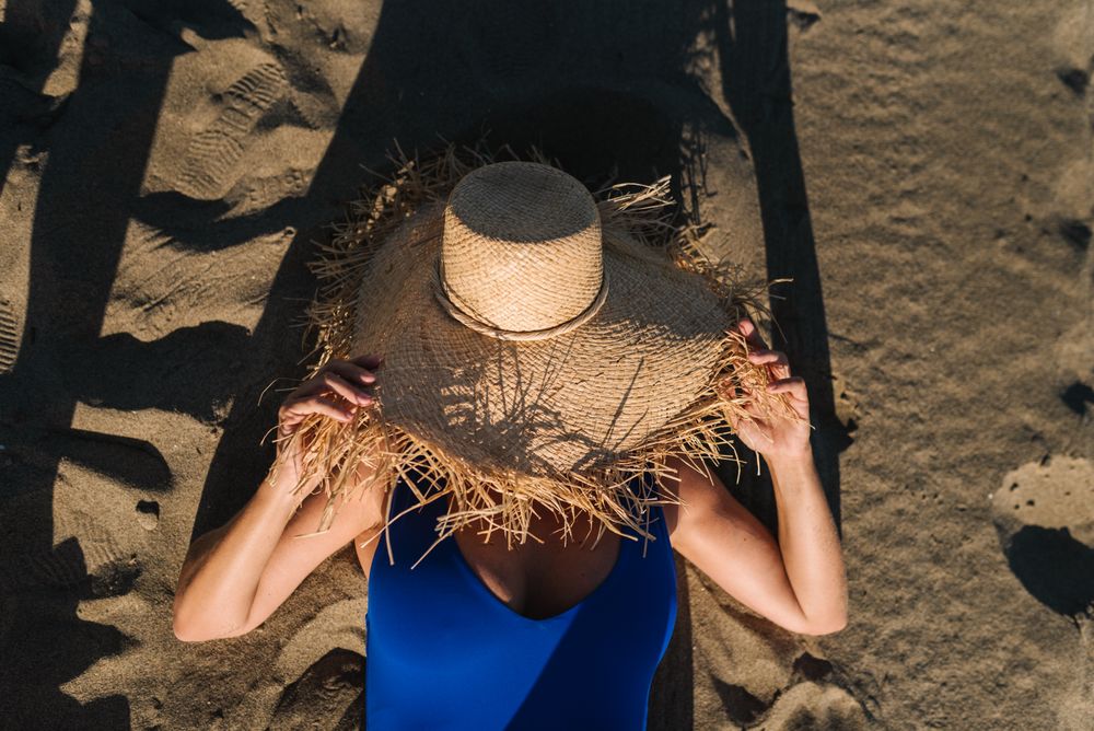 Woman putting hand behind head and lying on sun