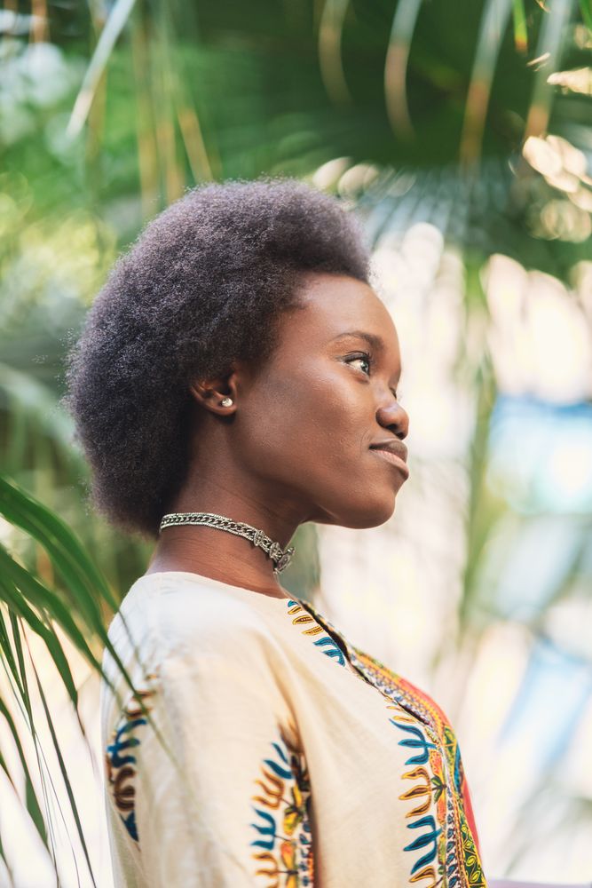Cheerful Black woman amidst palm leaves