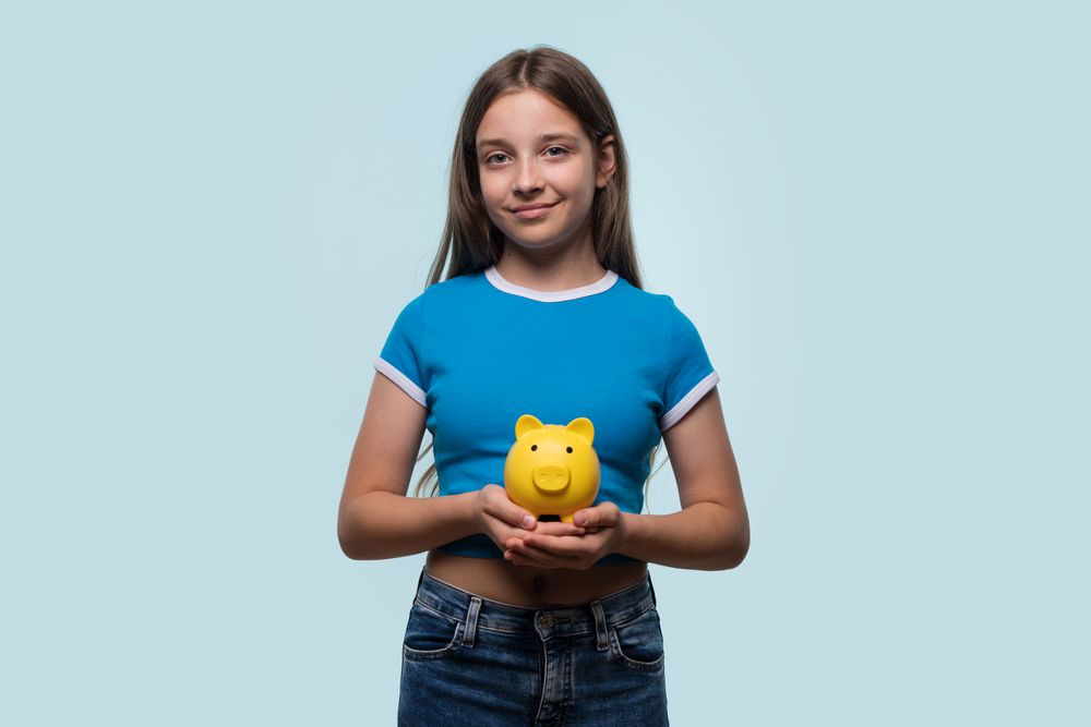 Girl smiling while holding yellow piggy bank