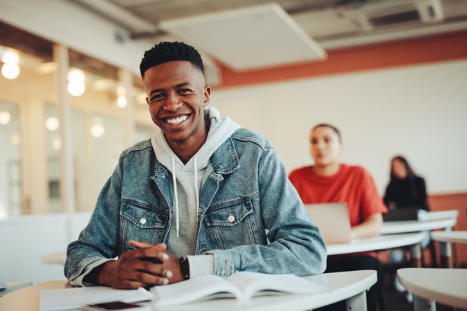 Young Black man sitting as desk in college classroom